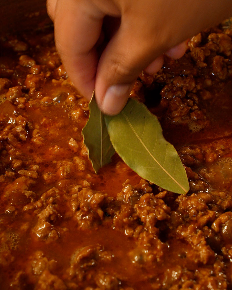 Bay leaves added to simmering Giniling sauce