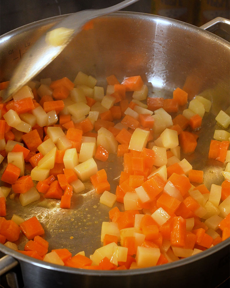 Diced potatoes and carrots frying in a pan for Giniling